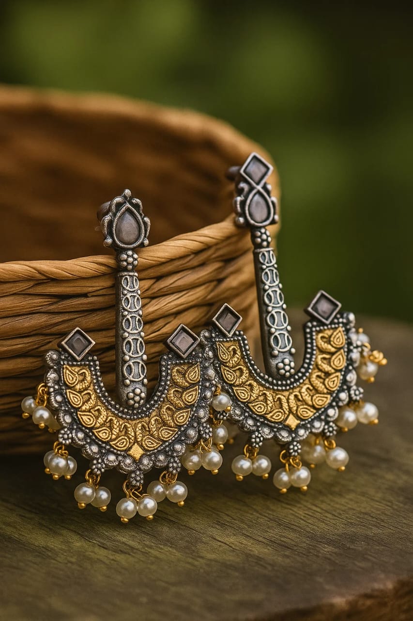 Ornate earrings with pearls on a wooden surface
