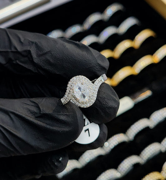 Diamond ring held by a gloved hand with a blurred jewelry display in the background
